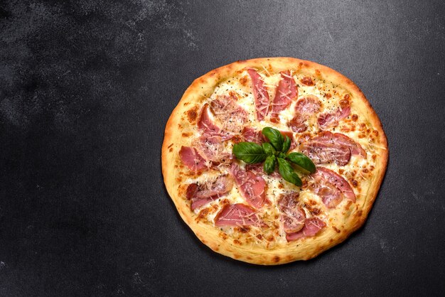 Delicious fresh crispy pizza from the oven with ham, cheese and\
basil. italian cuisine