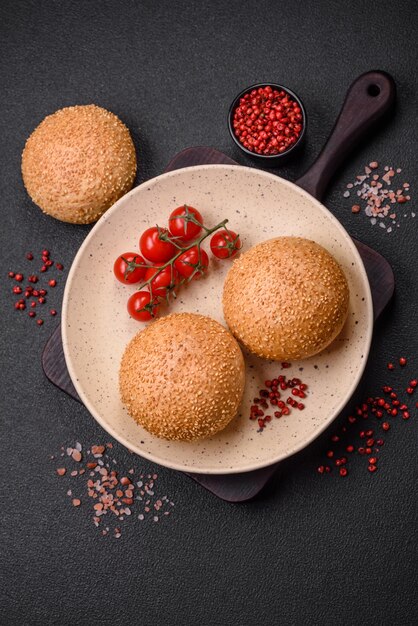 Delicious fresh crispy white round bread with seeds and grains on a dark concrete background