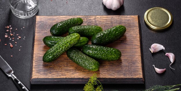 Delicious fresh cucumbers with garlic salt spices and herbs on a wooden cutting board