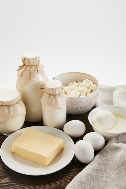 Delicious fresh dairy products and eggs on rustic wooden table with cloth isolated on white