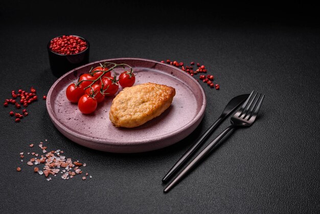 Delicious fresh fried vegetarian soybean cutlet with salt spices and herbs with vegetables on a ceramic plate on a dark concrete background