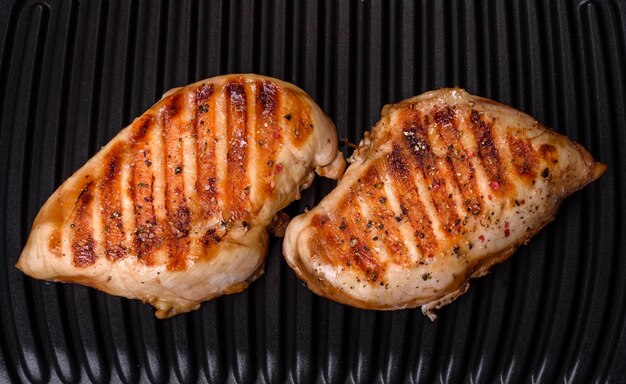 Delicious fresh grilled chicken fillet with spices and herbs on a dark concrete background A dish cooked over fire