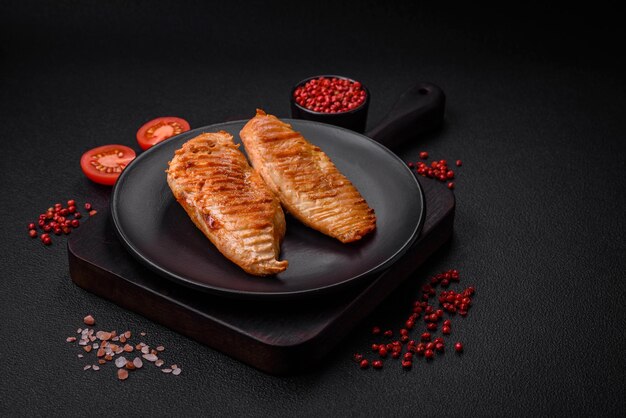 Delicious fresh grilled chicken fillet with spices and herbs on a dark concrete background