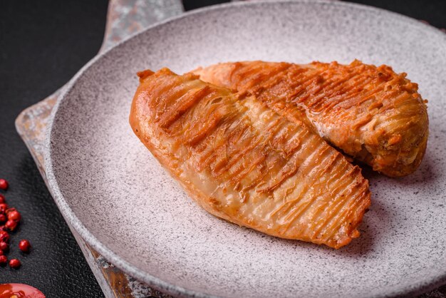 Delicious fresh grilled chicken fillet with spices and herbs on a dark concrete background