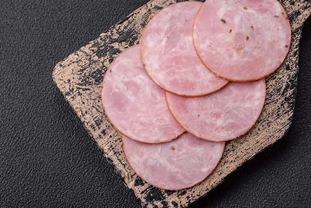 Photo delicious fresh ham cut into round slices with salt spices and herbs on a dark concrete background