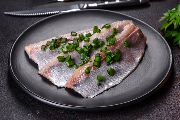 검은 접시에 소금 향신료와 허브를 넣은 맛있는 신선한 청어 필레