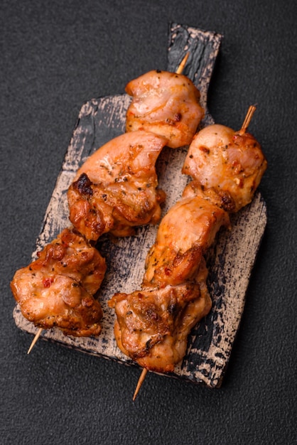 Delicious fresh juicy chicken or pork kebab on skewers with salt and spices on a dark concrete background