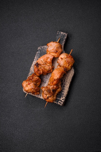 Delicious fresh juicy chicken or pork kebab on skewers with salt and spices on a dark concrete background