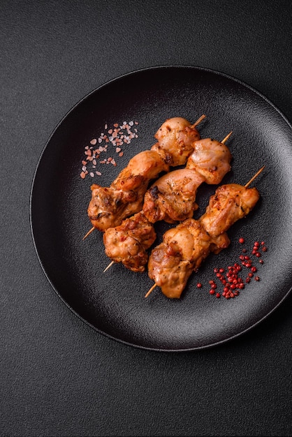 Delicious fresh juicy chicken or pork kebab on skewers with salt and spices on a dark concrete background