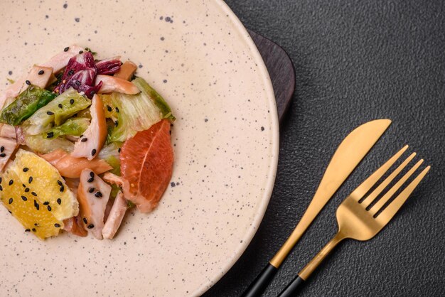 Foto deliziosa insalata fresca e succosa di sesamo lattuga pompelmo pollo a fette con olio d'oliva su un piatto di ceramica su uno sfondo di cemento