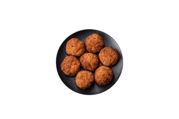 Delicious fresh meat or vegetable cutlets with spices and herbs on a black plate on a dark concrete background