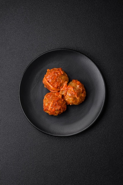 Delicious fresh meatballs from minced meat or fish with tomato sauce carrots onions salt and spices on a dark concrete background