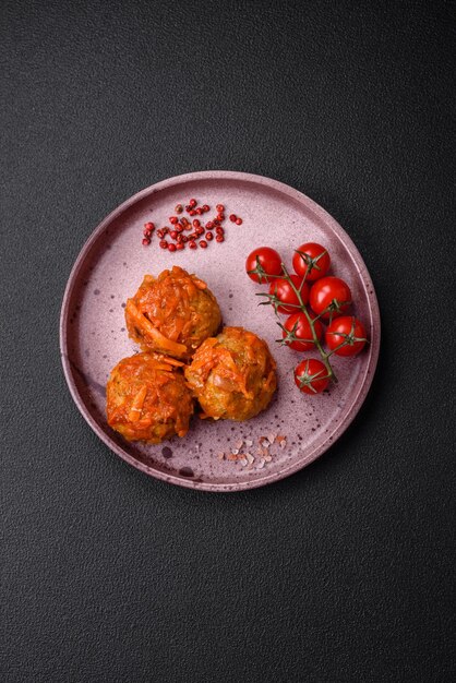 Delicious fresh meatballs from minced meat or fish with tomato sauce carrots onions salt and spices on a dark concrete background