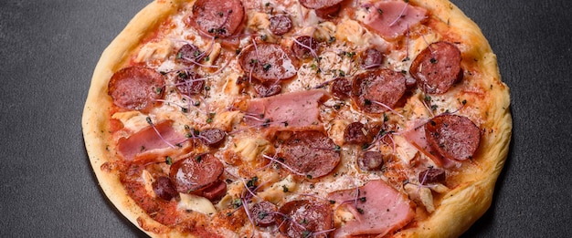 Delicious fresh oven pizza with tomatoes, salami and bacon on a dark concrete background. Italian cuisine