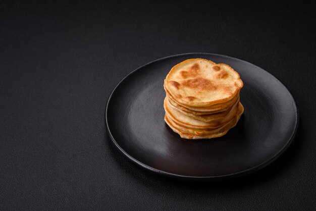 Delicious fresh pancakes with berry jam on a black ceramic plate