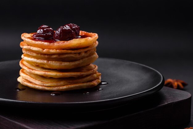 Delicious fresh pancakes with berry jam on a black ceramic plate