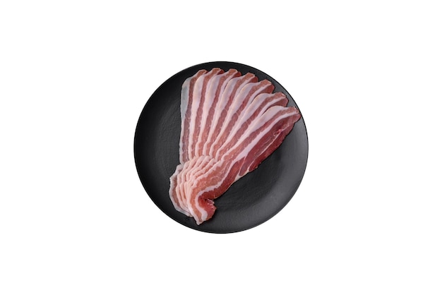 Photo delicious fresh pancetta with salt and spices cut into thin slices on a dark concrete background