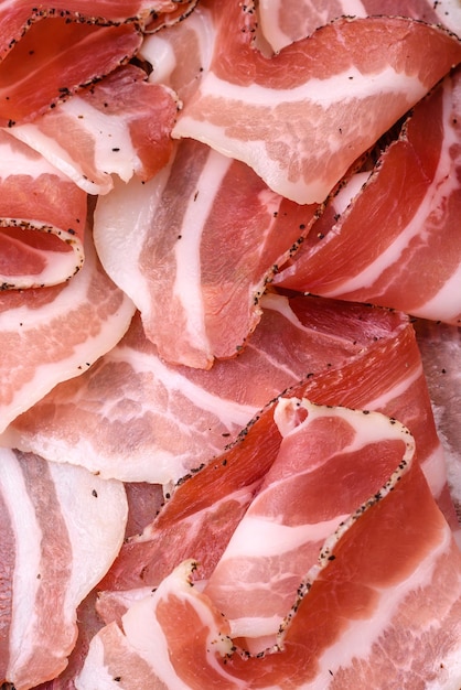 Delicious fresh pancetta with salt and spices cut into thin slices