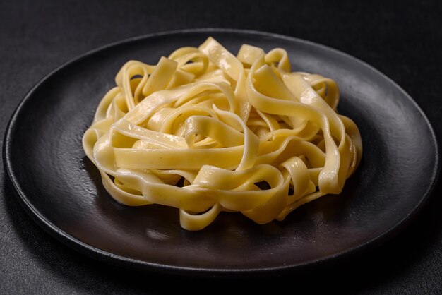 Delicious fresh pasta with pesto sauce and seafood on a black plate