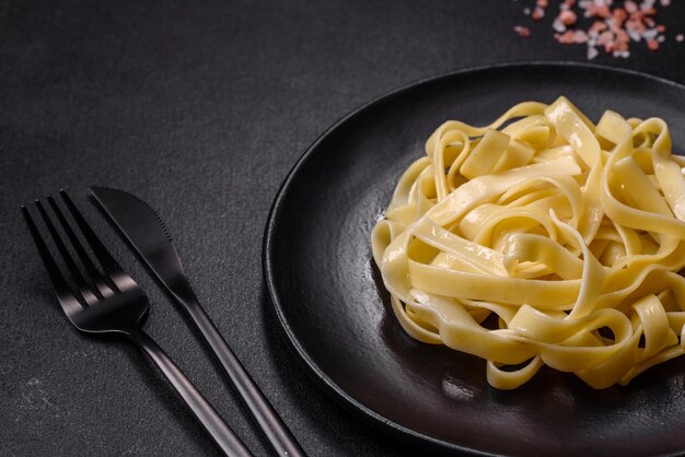 Delicious fresh pasta with pesto sauce and seafood on a black plate