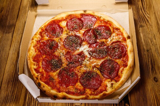 Delicious fresh pizza in cardboard box on a wooden table Concept for home delivery of food fast food delivery of pizza