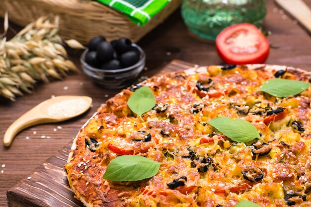 Delicious fresh pizza with chicken, tomatoes, cheese and black olives