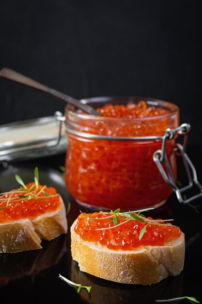 Delicious fresh red caviar with baguette toasts on dark background