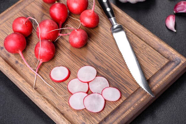 Foto delizioso ravanello rosso fresco come ingrediente per fare l'insalata di primavera sul tagliere di legno