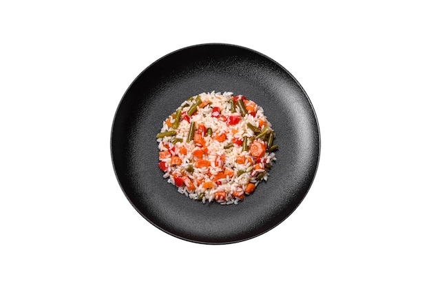 Delicious fresh risotto with vegetables spices and herbs on a black plate on a dark concrete background