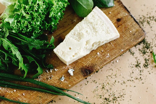 Delicious fresh salad arugula spinach and parmezan cheese on wooden cooking board top view