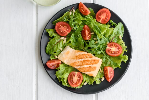 Delicious fresh salad with fish, tomatoes and lettuce leaves. Healthy food