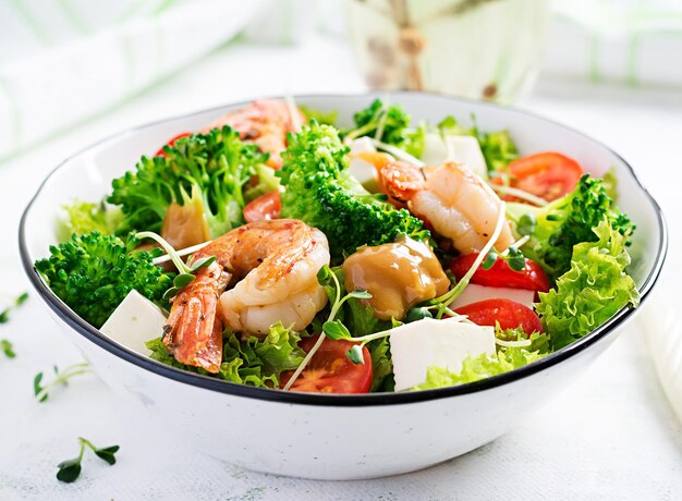 Delicious fresh salad with shrimps prawns broccoli feta cheese tomatoes lettuce and peanut dressing