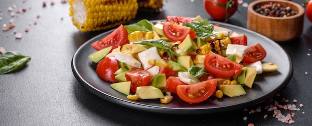 Delicious fresh salad with tomatoes, avocado, cheese and grilled corn with olive oil. Mediterranean cuisine