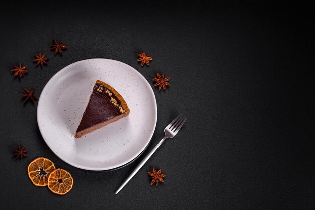 Delicious fresh sweet chocolate cake with nuts cut into slices on a dark concrete background