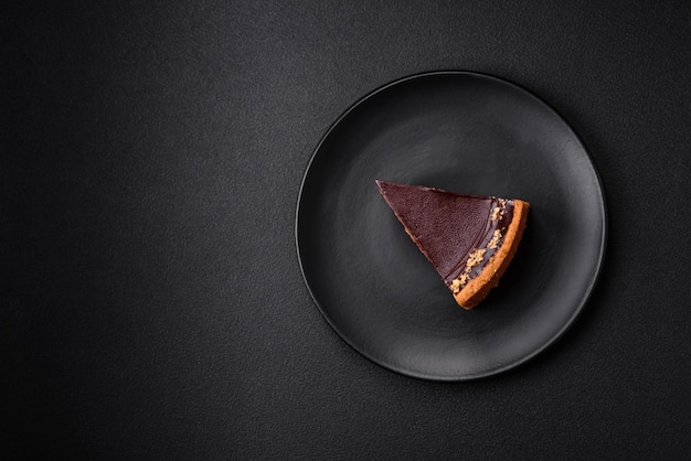 Delicious fresh sweet chocolate cake with nuts cut into slices on a dark concrete background