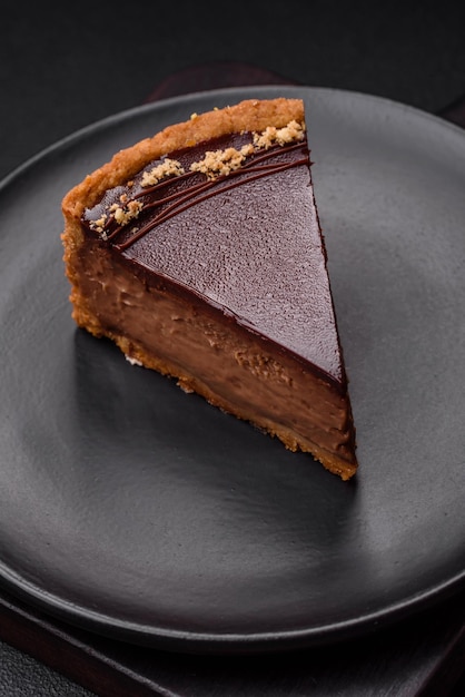 Delicious fresh sweet chocolate cake with nuts cut into slices on a dark concrete background