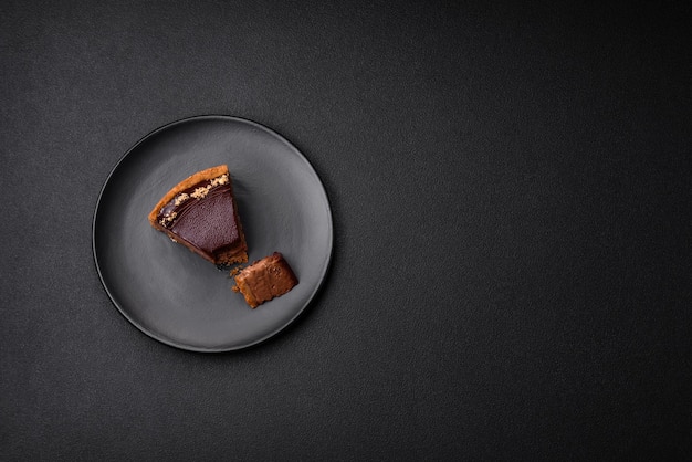 Delicious fresh sweet chocolate cake with nuts cut into slices on a dark concrete background