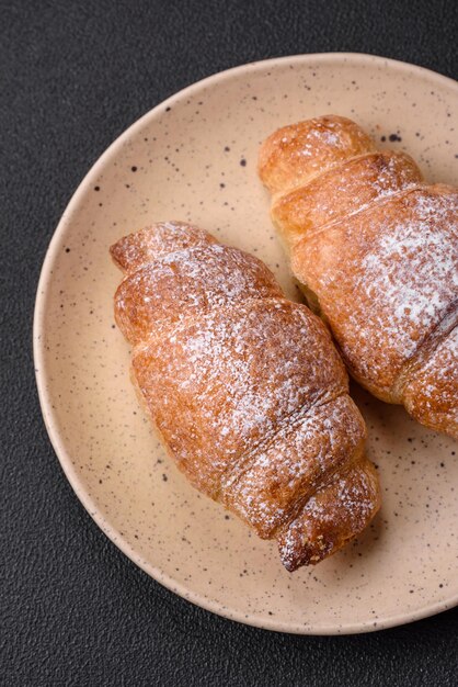 Delicious fresh sweet crispy croissants with chocolate cream on a ceramic plate on a dark concrete background