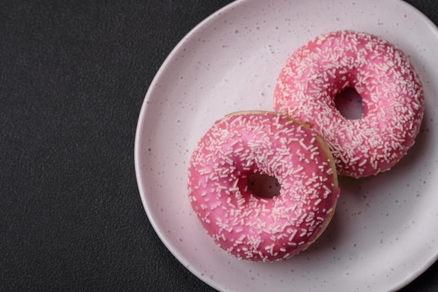 Вкусные свежие сладкие пончики в розовой глазури с клубничной начинкой