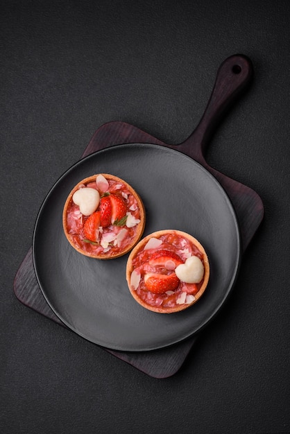 Delicious fresh sweet tartlets with strawberries and coconut flakes