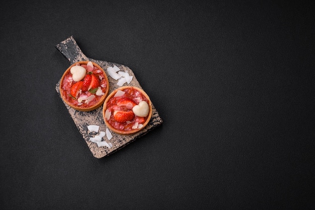 Delicious fresh sweet tartlets with strawberries and coconut flakes