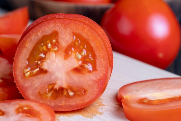 Вкусный свежий помидор, нарезанный кусочками на столе