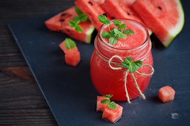 Delicious fresh watermelon smoothie on the dark wooden background. Healthy food concept.