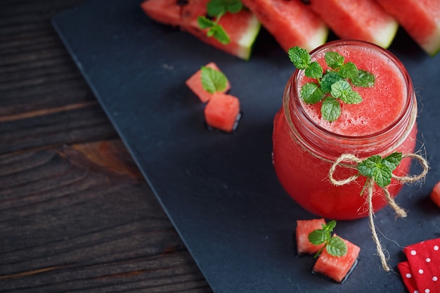 Delicious fresh watermelon smoothie on the dark wooden surface