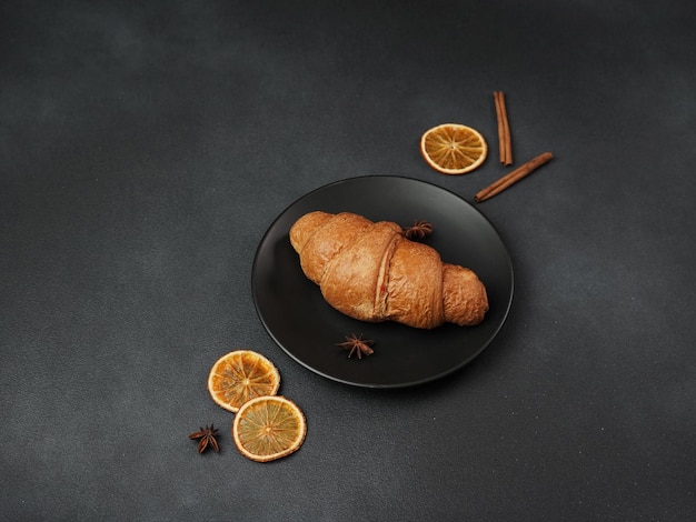 Photo delicious freshly baked croissant lying on a black plate against a black background