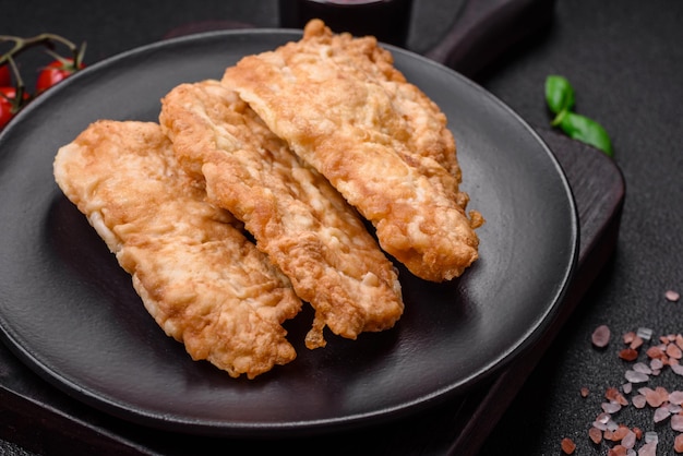 Delicious fried chicken chop or pork meat fried breaded with salt spices and herbs on a dark concrete background