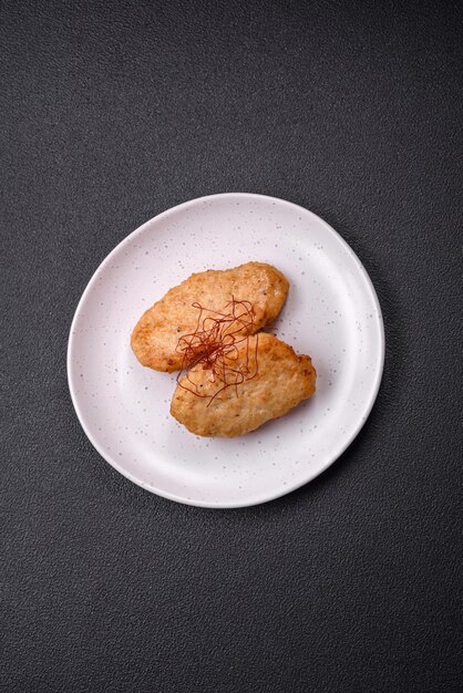 Delicious fried cutlets or meatballs with salt spices and herbs on a dark concrete background