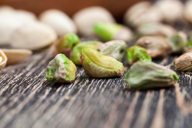 Delicious fried salted pistachio nuts, pistachios on a wooden table during cooking