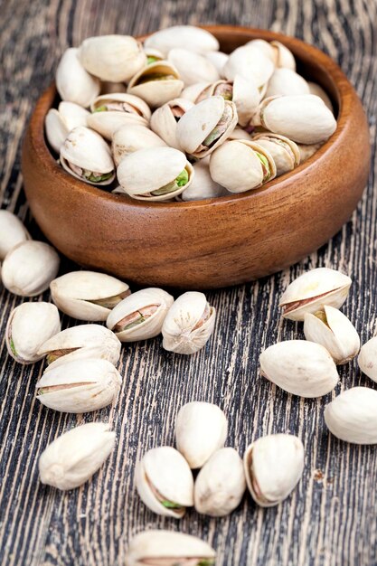 delicious fried salted pistachio nuts, pistachios on a wooden table during cooking