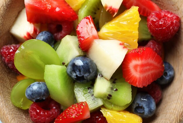 Delicious fruit salad in wooden bowl closeup